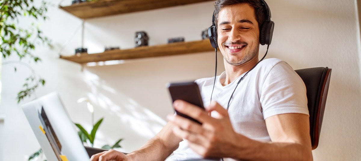 Man listening music while working on laptop
